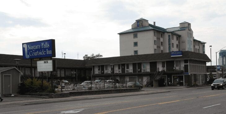 A multi-story motel with parked cars along the street in front.